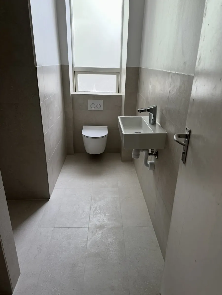 Efter: toiletrum med væghængt toilet, berøringsfri armatur og store fliser