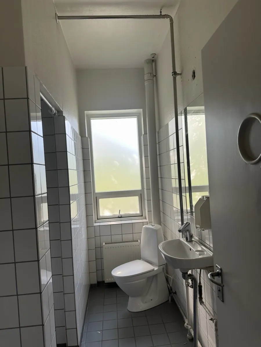 Før: toiletrum med synlige rør, gulvstående toilet og små fliser